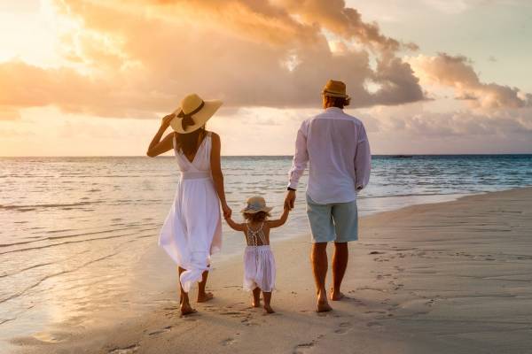 Family Walking On Beach At Sunset