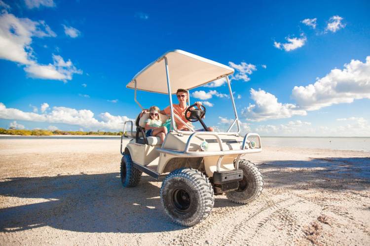 Dad and daughter on a golf cart on the beach