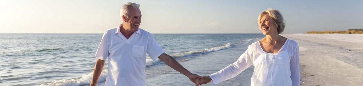 Snowbirds holding hands and walking on the beach in Texas